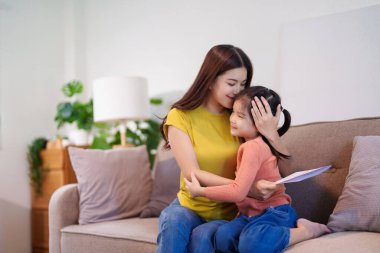 Anne, düşünceli bir el yapımı kart aldıktan sonra kızını sıcak bir şekilde kucaklıyor ve o anın tadını çıkarıyor..