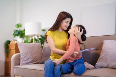 Anne, düşünceli bir el yapımı kart aldıktan sonra kızını sıcak bir şekilde kucaklıyor ve o anın tadını çıkarıyor..