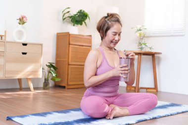 Evdeki yoga seansından sonra kıdemli Asyalı kadın smoothie içiyor.