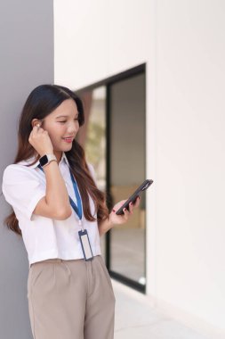 Modern bir iş bölgesinde, Asyalı iş kadını, kablosuz kulaklıkla konuşuyor.