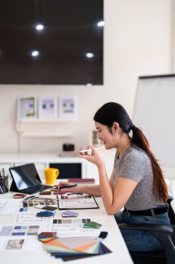 Tasarım stüdyosunda renk ve malzeme seçimi üzerinde çalışırken iç mimar iş görüşmesi yapıyor