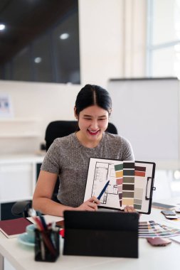 Yaratıcı ofiste online toplantı sırasında tablet aracılığıyla iç tasarım fikirleri sunan genç mimar