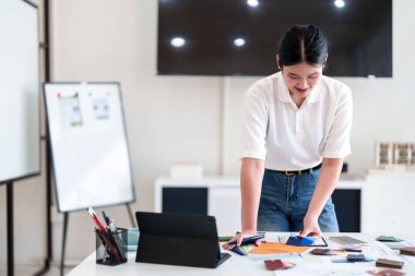 Genç mimar modern iç tasarım çalışma istasyonunda dururken malzeme ve renk örnekleri seçiyor