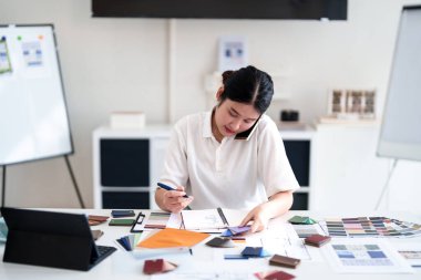 Tasarım stüdyosunda renk ve malzeme seçimi üzerinde çalışırken iç mimar iş görüşmesi yapıyor