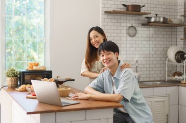 Neşeli bir çift mutfaktaki video görüşmesinden zevk alıyor. Taze yiyecek ve içeceklerle birlikte.