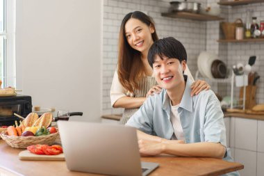 Neşeli bir çift mutfaktaki video görüşmesinden zevk alıyor. Taze yiyecek ve içeceklerle birlikte.