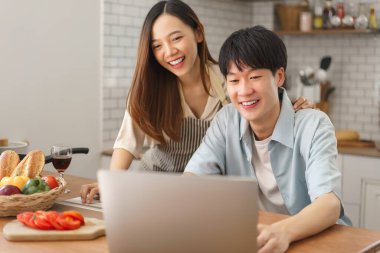 Neşeli bir çift mutfaktaki video görüşmesinden zevk alıyor. Taze yiyecek ve içeceklerle birlikte.