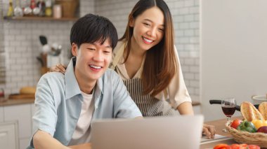 Neşeli bir çift mutfaktaki video görüşmesinden zevk alıyor. Taze yiyecek ve içeceklerle birlikte.