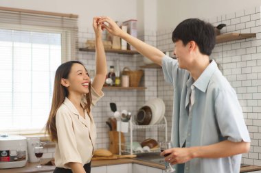 Samimi bir mutfak ortamında birbirine gülümseyen mutlu genç bir çift.