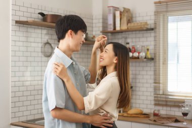 Samimi bir mutfak ortamında birbirine gülümseyen mutlu genç bir çift.