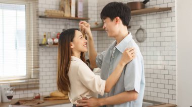 Samimi bir mutfak ortamında birbirine gülümseyen mutlu genç bir çift.