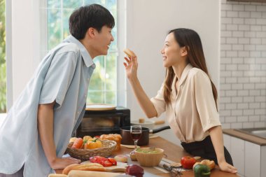 Neşeli çift sohbet ediyor, gülüyor ve birlikte yemek pişiriyorlar.