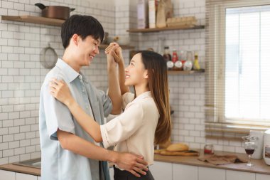 Samimi bir mutfak ortamında birbirine gülümseyen mutlu genç bir çift.