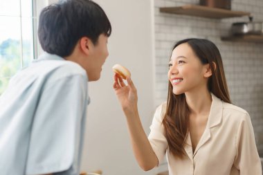 Neşeli çift sohbet ediyor, gülüyor ve birlikte yemek pişiriyorlar.