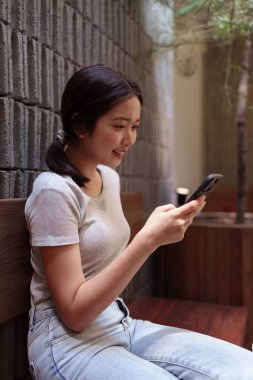 Kadın rahat kafeterya masasında akıllı telefonlara bakarken huzur içinde kahve molası veriyor.