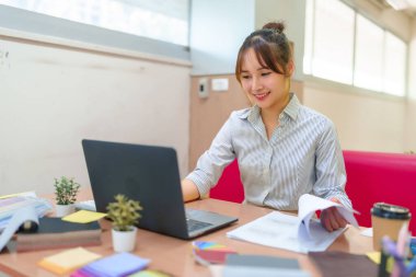 Genç bir Asyalı kadın dizüstü bilgisayarında renk örnekleri ve planlarla dolu bir masada iç dizayn eğitimi görüyor. Eğitim için ideal, yaratıcı öğrenme kavramları.