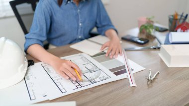 Asyalı genç mimar, modern ev tasarımlarına odaklanarak ev planı tasarımı için plan çiziyor. Bak Asyalı bir kadın tasarımcı nasıl bir kat tasarımı planı hazırlıyor. Mimarın çizim planı uzman mimari çalışmaları sergiliyor.