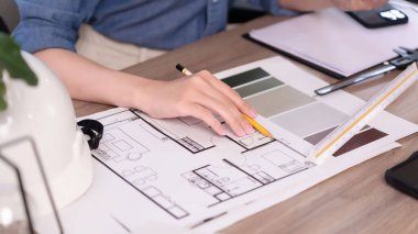 Asyalı kadın el mimarı titizlikle yeni bir ev iç mimarisi tasarlıyor. Hassas aletlerle birlikte. Asyalı kadınların elinin mimari konsepti, yenilikçi bir konut alanı için ayrıntılı bir ev tasarımı planı ve renk paletleri üzerinde yoğunlaşır..