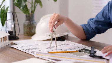 Asyalı kadın eli, ev planı için mimari bir pusula kullanıyor. Bu Asyalı kadın mimar bir inşaat mühendisliği tasarımı projesi yaratıyor. İç mimar için detaylı bir tasarım burada..
