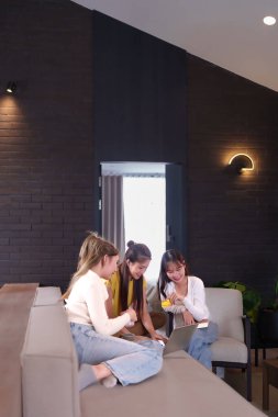 Bir grup Asyalı genç bayan arkadaş kredi kartı ve dizüstü bilgisayar kullanarak online alışveriş yapıyorlar. Moda kıyafetleri ya da ev dekorasyonu için online mağazalara bakıyorlar.