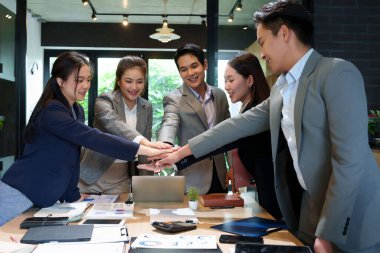 İş yerinde hedef ve hedeflere ulaşmak için takım çalışması birliği ve işbirliği örneği gösteren bir toplantı sırasında, Asyalı yetişkin iş adamlarının el ele tutuşması motivasyonu