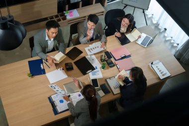 Asyalı yetişkin iş adamlarının veri tabloları, grafikleri ve raporları gözden geçirdikleri bir toplantıda üst düzey görüşleri. Strateji geliştirme için takım çalışması işbirliğini vurguluyor