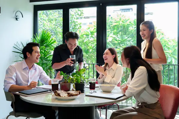 Bir grup neşeli Asyalı yetişkin iş adamı modern bir ofiste takım çalışması yaparak başarıyı kutluyorlar. Bu mutlu bir şirket toplantısı.