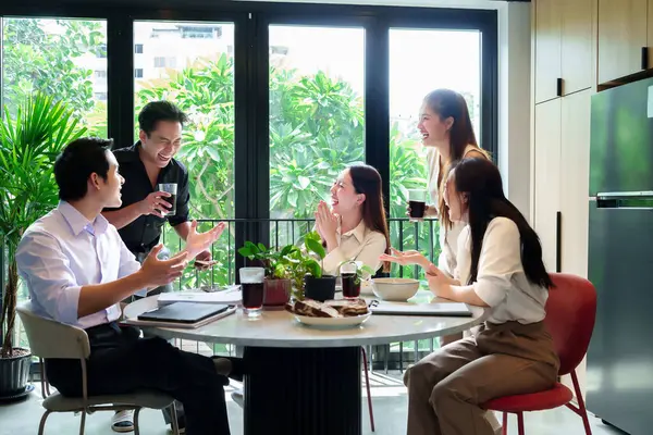 Canlı bir ofiste neşeli bir iş birliği yakaladık. Genç Asyalı profesyoneller fikir alışverişinde bulundular ve birlikte içki içtiler.