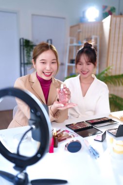 İki genç Asyalı kadın canlı yayında makyaj ve cilt bakımı için özel ders veriyorlar. Güzellik blogcusu internette cilt ürünü ve makyaj için güzellik tavsiyelerini paylaşıyor.