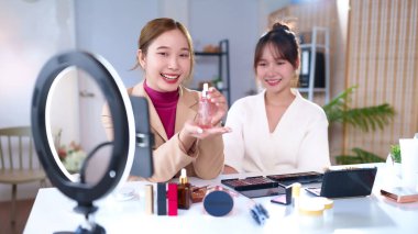 Sosyal medyada iki genç Asyalı kadın güzellik ürünü sunuyor. Vlog 'larında ipuçlarını paylaşıyorlar, ev stüdyolarındaki izleyicileri için kozmetik ürünler hakkında ilgi çekici içerikler yaratıyorlar..