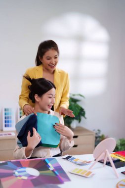 Asyalı bir kadın stilisti, müşterilerine gardırobu için renk örnekleri kullanarak mükemmel renk paletleri bulmalarında yardımcı olur. Moda ipuçlarıyla kişisel renk sezonunu belirler.