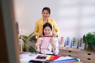 İki Asyalı kadın kişisel renk danışmanlığı yapıyorlar. Genç bir kadın güzellik ve moda için uygun renkler bulmak için bir stilistten renk analizi yardımı alıyor..