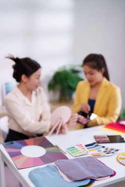 İki genç Asyalı kadın, moda ve güzellik danışmanlığı tavsiyeleri için mükemmel makyaj gölgeleri ve mevsimsel tonları seçerek kişisel renk analizini tartışıyor.