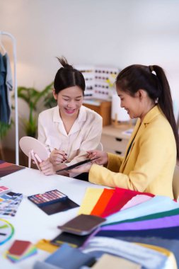 İki Asyalı yetişkin kadın, stüdyodaki renk örnekleriyle moda için doğru renk ve makyajı seçmeleri için kişisel renk eşleştirmesi için danışmanlık yapıyorlar..