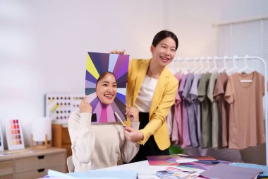 Genç Asyalı kadınlar kişisel renkleri kostüm için kumaşlarla analiz ediyorlar. Stilist en iyi giysi gözlüklerini bulmaya yardım ediyor. Moda ve güzellik kavramı.