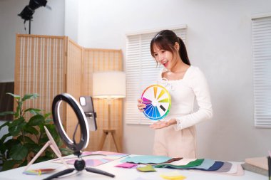 Kişisel renk analizini Asyalı yetişkin bir kadının tekerlek kullanarak renk teorisini açıklamasıyla çevrimiçi koçluk yaparak öğrenin. Mükemmel kıyafetlerinizi ve makyajınızı seçin..