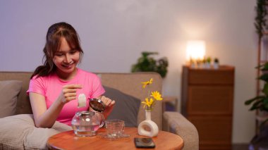Genç bir Asyalı kadın evde çay hazırlıyor, kendi başının çaresine bakıyor. Çay hazırlamak günlük sağlık ve evde rahat olmak için idealdir..