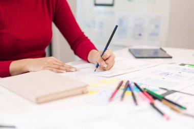 Asyalı kadın elleri mobil uygulama ve web sitesi için arayüz düzeni üzerinde çalışıyor. Beyaz masadaki kullanıcı arayüzü deneyimi için yaratıcı süreç kavramı