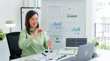 Asyalı kadın iş kadını rüzgar türbini güneş paneli modelleriyle yenilenebilir enerji sürdürülebilirliğini destekliyor