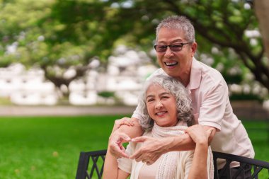 Neşeli yaşlı Asyalı kadın ve erkek parkta birbirlerine sevgi ve sevgi gösteriyorlar.