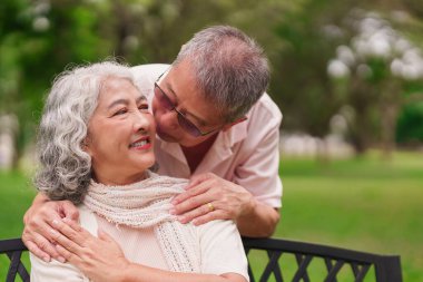 Neşeli, son sınıf Asyalı çift, sevgi dolu öpücük parkı banklarında emeklilik hayatlarını kutluyorlar. Mutlu bir aşk ilişkisi.