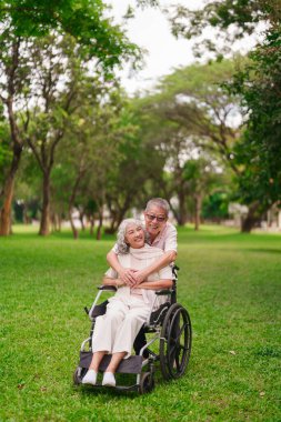 Mutlu Asyalı yaşlı çift şefkat gösteriyor. Açık havada karşılıklı destek veriyorlar. Huzur parkı kuruyorlar.