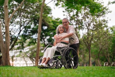 Asyalı yaşlı çift, emeklilik sonrası yaşam tarzının mutluluğu için park desteğini, kadınları, tekerlekli sandalyeleri seviyor.