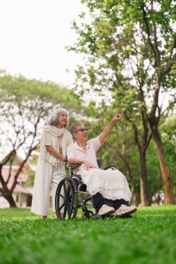 Tekerlekli sandalyeli Asyalı yaşlı çift emeklilik zamanlarında sevgi dolu ve destekleyici bir ilişki paylaşıyorlar.