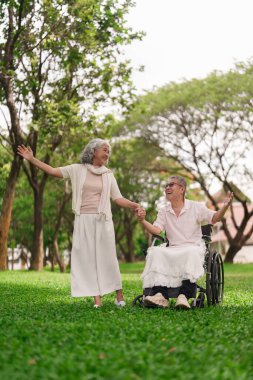 Neşeli Asyalı son sınıf öğrencisi erkek ve kadın parkta el ele tutuşarak mutlu anları paylaşıyorlar.