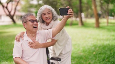 Neşeli Asyalı son sınıf öğrencisi kadın mutlu anı yakalıyor akıllı telefon parkı emeklilik mutluluğu açık hava keyfi.