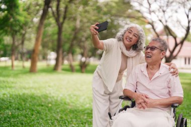 Asyalı son sınıf öğrencisi fotoğraf çekiniyor. Parkta güneşli bir gün geçiriyor. Bağlantı kuruyor.