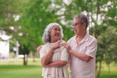 Yaşlı Asyalı koca, emekli olduktan sonra halka açık bir parkta gülümseyerek mutlu bir anı paylaşıyor..