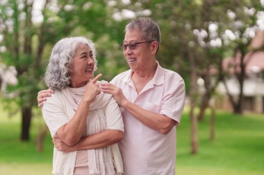 Asyalı yaşlı çift dışarıda mutlu anlarını paylaşıyor. Emekli hayat arkadaşlığının tadını çıkarıyorlar.