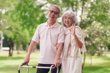 Neşeli Asyalı son sınıf öğrencisi karı koca güneşli bir parkta mutlu mesut dururlar. Sağlıklı yaşam tarzının keyfini çıkarırlar.